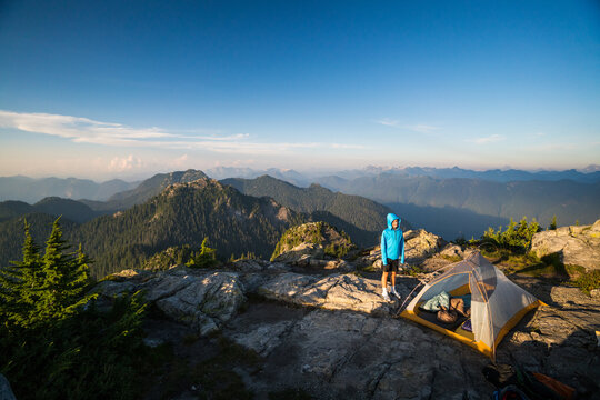 Backpacker stands by tent on rocky mountaintop