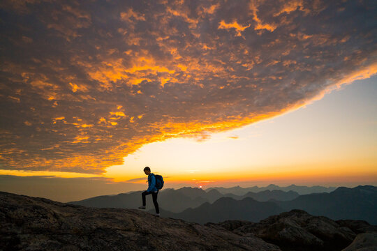 Lone hiker ascending a mountain at spectacular sunrise