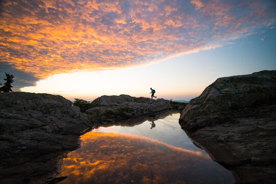 Man trail running across a rocky ridge at sunrise