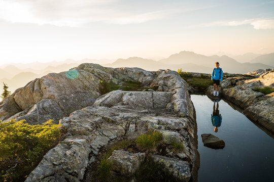 Young boy stands by a mountain pool at sunrise