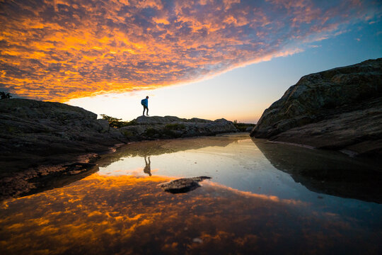 Hiker standing on rocks watching a dramatic sunset