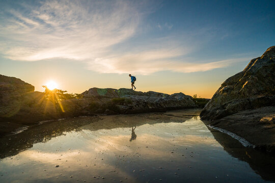 Man hiking on a rocky shoreline at sunset
