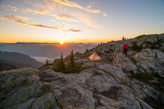 Woman walking near tent at scenic mountain sunrise