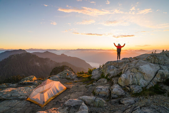 Hiker celebrates on a mountain top at sunrise