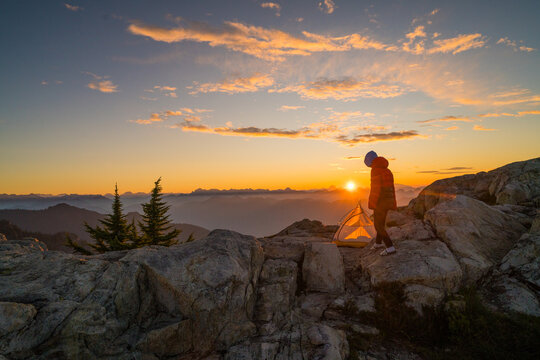 Hiker enjoys a golden sunrise from mountain campsite