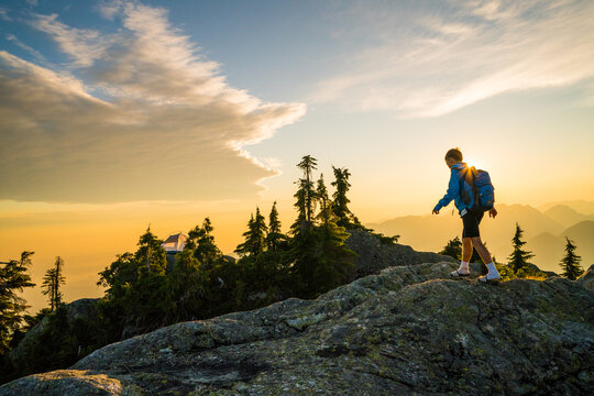 Young boy hikes along a mountain summit at sunset