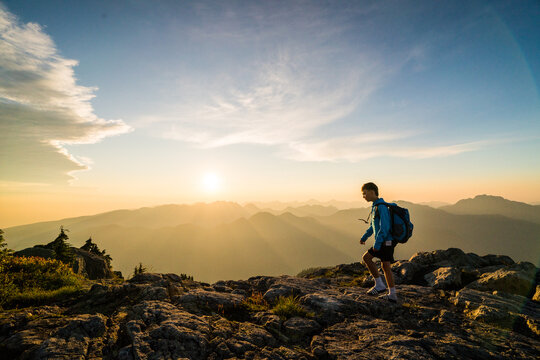 Young man hiking on a rocky mountain at sunrise
