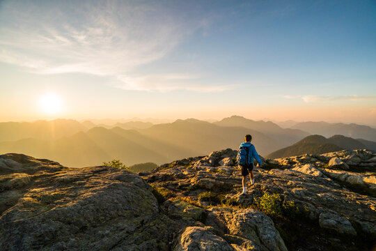 Hiker walks along a mountain summit at sunset