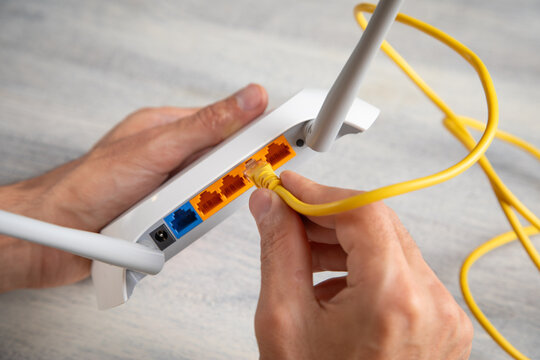 Man plugging internet cable into wifi router.