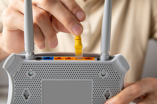 Man plugging internet cable into wifi router.