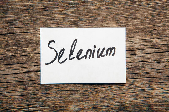 Sheet of paper with word selenium on wooden background.