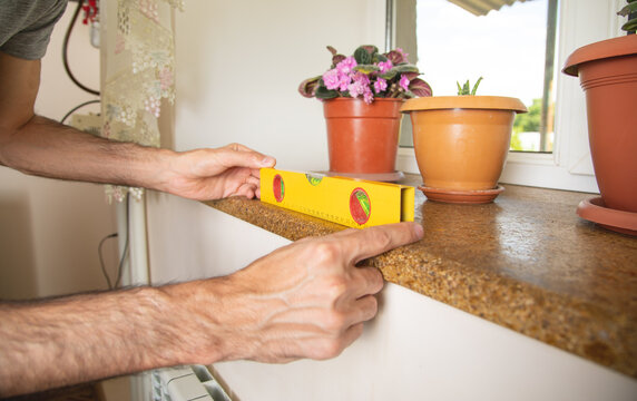 Worker using bubble level on windowsill at home.