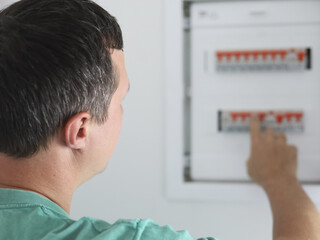 Fototapeta premium Technician Performing Electrical Panel Safety Check. Electrician Checking Circuit Breakers In Home Electrical Panel. Man checking and operating circuit breakers