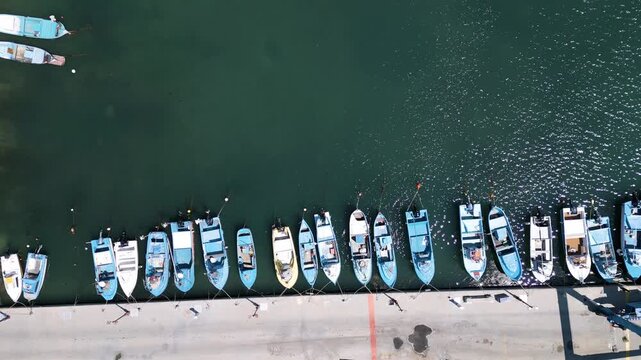 Aerial top down view of small fishing boats moored at the pier in harbor