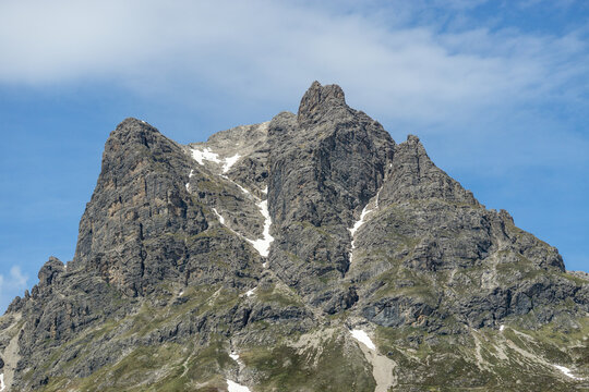 Summit Aries stone and red flowered colored meadows and K&ouml;rber lake in the alps of Bregenzerwald, with rocky mountains and steep, stony slopes on a sunny day with veil clouds.