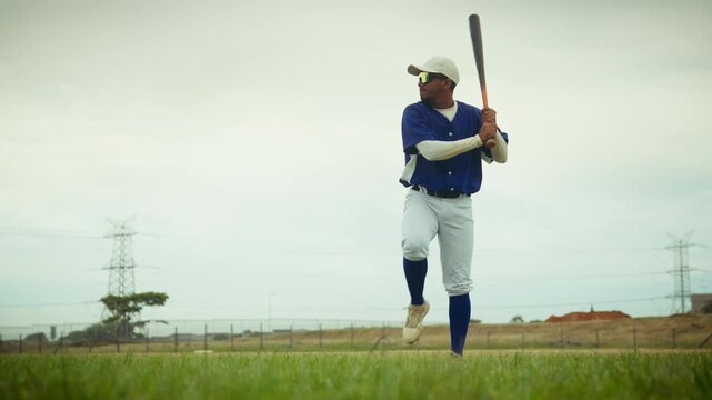 A determined baseball player in uniform hones his batting stance and swing on the field, focused on perfecting his technique before a game.