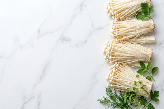 Fresh enoki mushrooms with green herbs on a white marble background