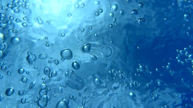 Bubbles rise to the surface as sunlight filters through clear water in vibrant summer pool oasis. Relaxation and refreshment concept highlight serene underwater experience