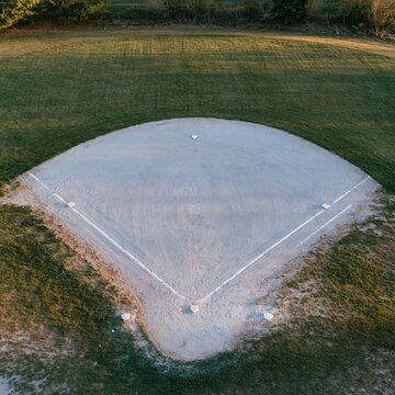 Overhead view of a baseball diamond with raked clay and mown grass showing a calm and luminous atmosphere for community recreation and sports facility design