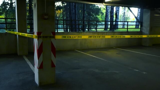 Yellow crime scene tape restricting access to an empty parking spot in a dimly lit garage, with trees visible in the background as the sun rises, creating a mysterious and tense atmosphere