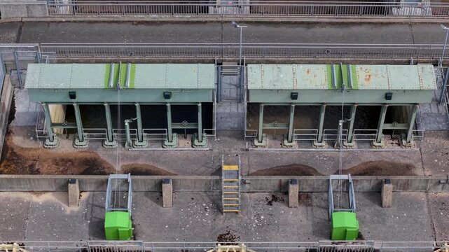 Close-up aerial view of a civil engineering tail sluice, flood defense barrier, and river water management system near King's Lynn, UK.