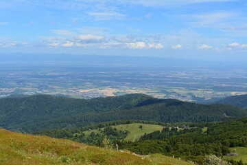 Fototapeta premium Panoramic view of a lush green mountain valley landscape during a bright and sunny summer afternoon