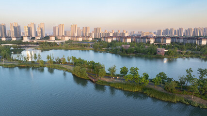 Obraz premium Aerial View of Urban Lake Park and Modern City Skyline at Sunset