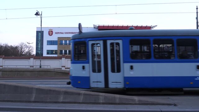 Krak&oacute;w, Poland - March 10, 2026. A view of the Medicine University with a tramway and a bus passing in front. 