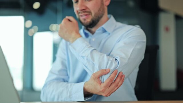 Close up of corporate manager or IT specialist suffering from elbow ache, tendonitis or arm inflammation at laptop. Tired employee or freelance designer feeling severe joint pain during office work