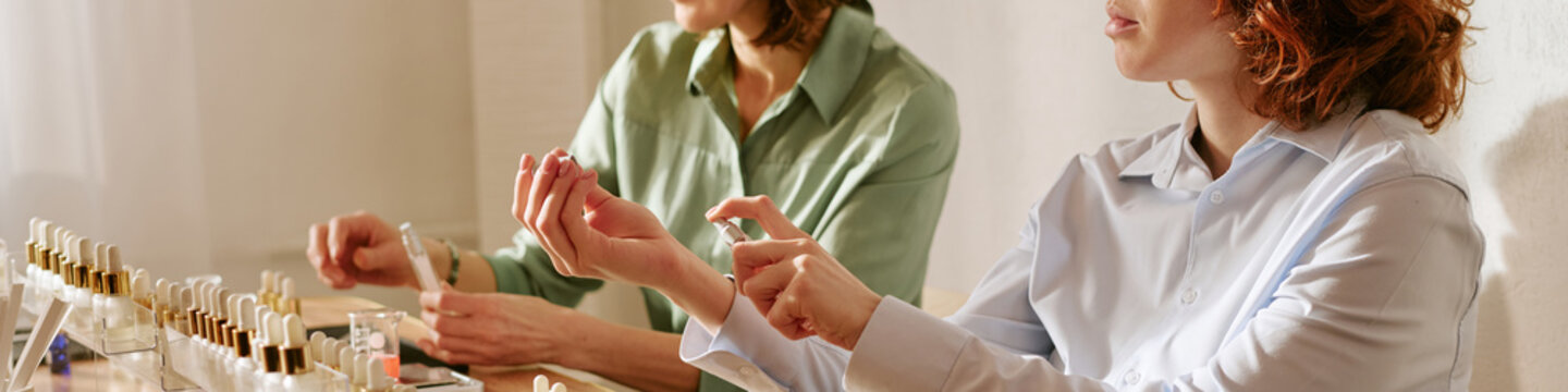 Website banner of women testing perfume samples and spraying fragrance on wrists during product selection, showing beauty retail decision making