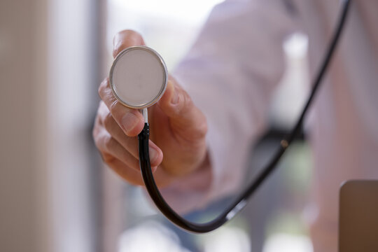 Doctor holding a stethoscope during a medical examination in a healthcare clinic. Professional physician symbolizing diagnosis, patient care, preventive medicine healthcare services.