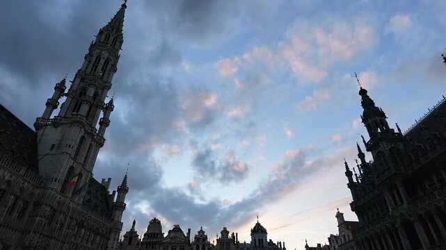 Grand Place Belgium sunset. Low-angle 4K video looking up at the majestic Gothic tower of the Brussels Town Hall between historic guild houses in the famous Grand Place market square.