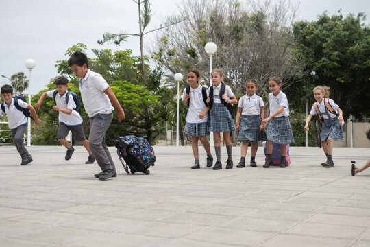 Group of elementary school children running and playing in the school courtyard before class