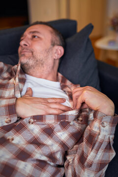 Man with heart problems, chest and abdominal pain at home measuring and checking pulse.