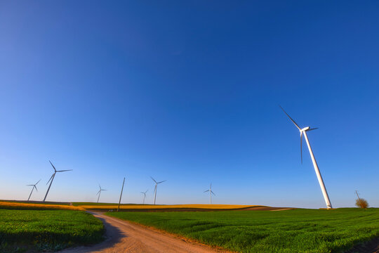 Wind turbines at sunset in green field &ndash; renewable energy, clean power, sustainable future.