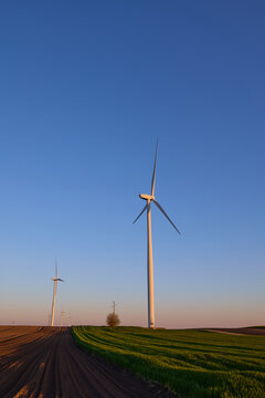 Wind turbines at sunset in green field &ndash; renewable energy, clean power, sustainable future.
