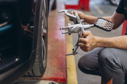 Mechanic adjusting wheel alignment using specialized tools on a car in a professional auto service garage