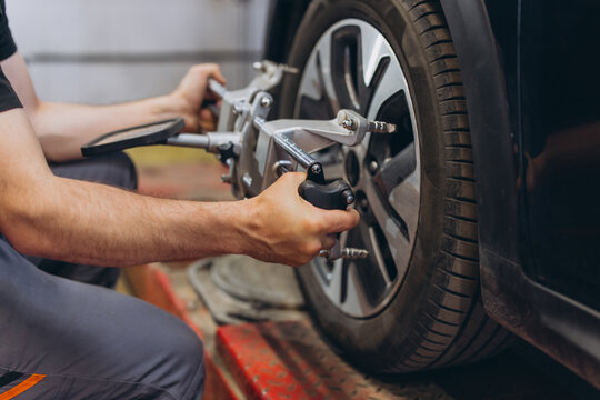 Car mechanic doing tire alignment and suspension check on a car wheel, service and maintenance in garage