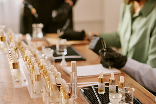 Close up of middle aged woman filling cosmetic serum bottles and recording notes during product testing. Ideal for skincare manufacturing, beauty brand content, quality control