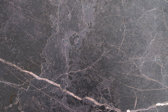 Dark marble slab with pale veining on textured surface
