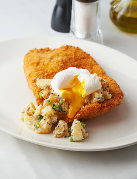 Crispy breaded chicken cutlet with creamy potatoes and poached egg, restaurant menu, comfort food concept