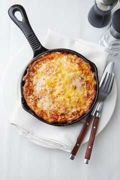 Baked cheese and bacon dish in cast iron skillet with melted cheese, restaurant menu, comfort food concept