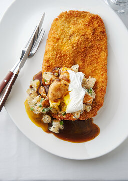 Crispy breaded chicken cutlet with creamy potatoes and poached egg, comfort food concept. Upscale restaurant menu, gourmet dining experience