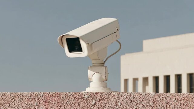 Outdoor security cameras mounted on a textured wall overlooking a building