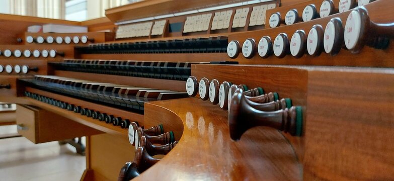 Pipe organ console with manuals keyboards and register knobs close up