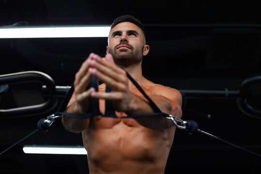 Fit and muscular man trains pectoral muscles on a block simulator in the gym.