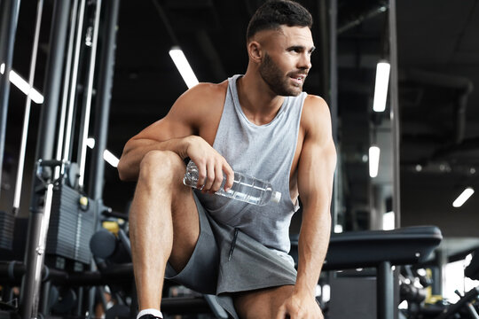 Sporty man resting, having break drinking water after doing exercise.