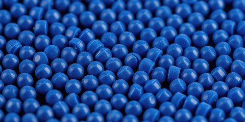 Fototapeta premium Many small blue plastic pellets fill frame. Pellets have smooth rounded shapes and consistent blue color. Background is dark. Material is useful for manufacturing industry.
