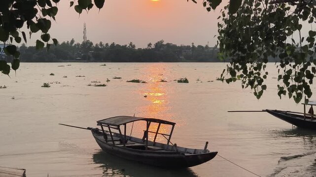A cinematic sunset view of a traditional wooden boat anchored at Rani Rashmani Ghat on the Hooghly River in Kolkata, West Bengal, featuring authentic local atmosphere.