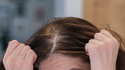 Naklejka premium Woman gently parts her hair with fingers. Her hands show care and curiosity.